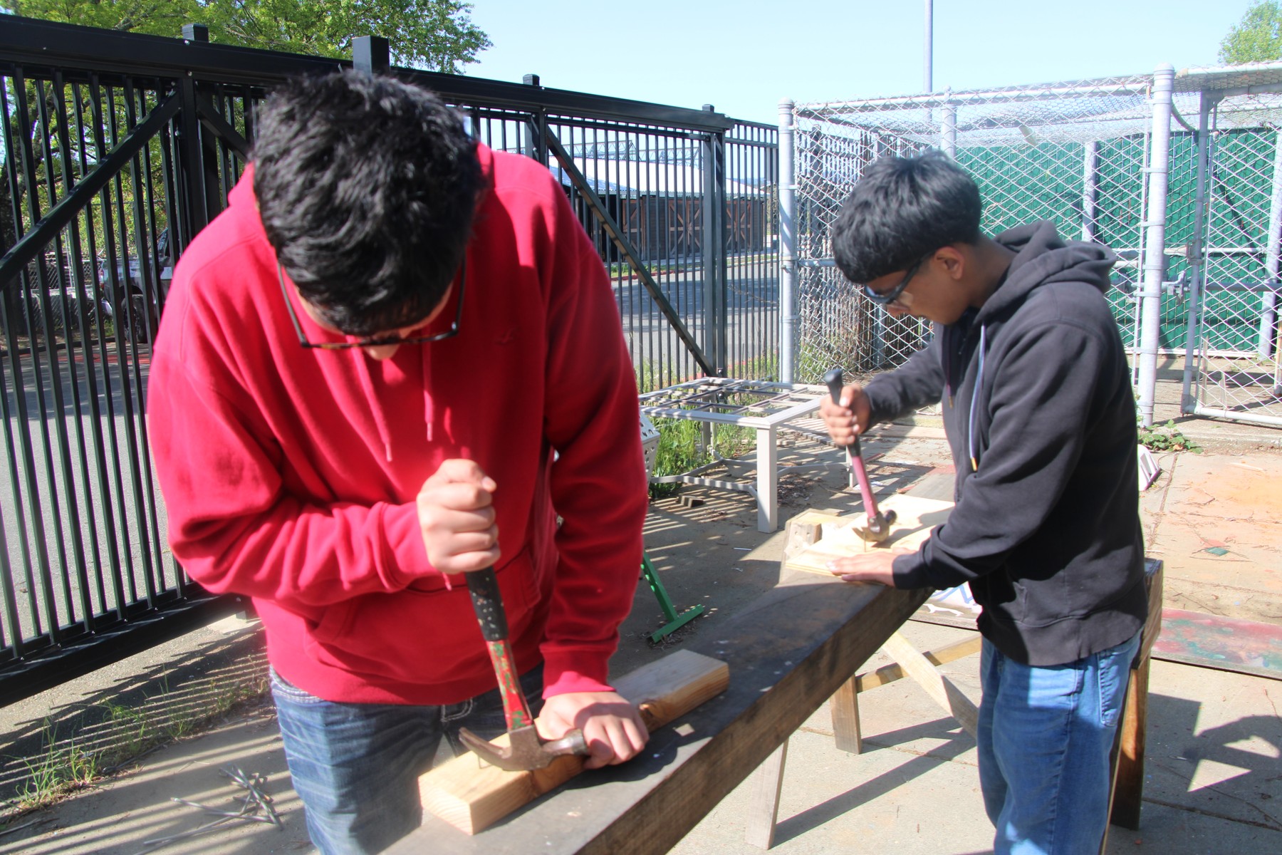 Two students practicing woodworking outdoors