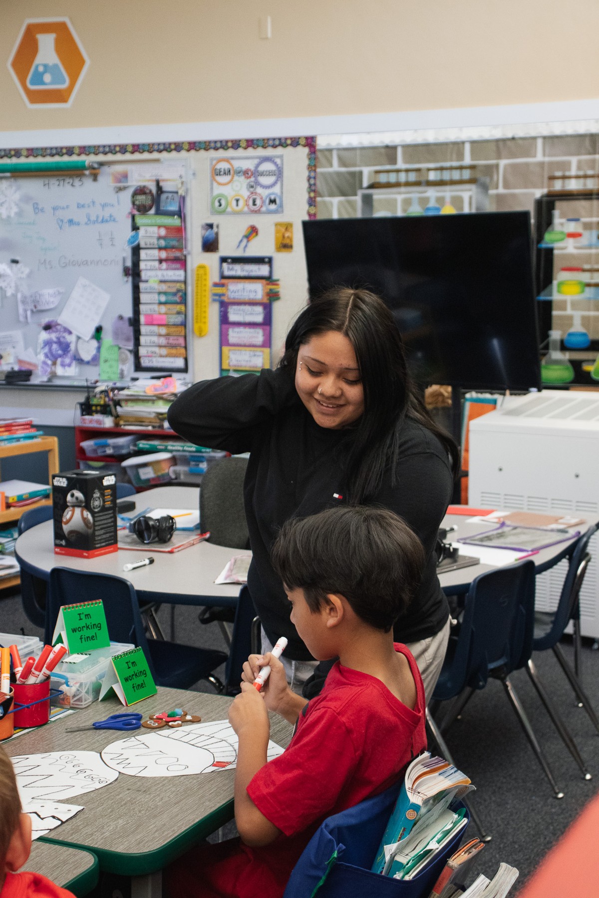 A student supporting a younger child in a classroom