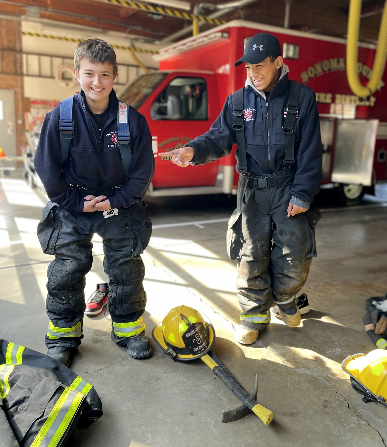 Two participants in firefighter gear beside a fire engine